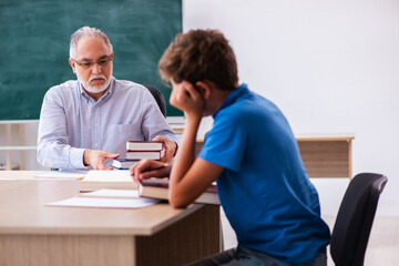 Old male teacher and schoolboy in the classroom
