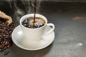 The steam from Pouring coffee into cup , A cup of fresh coffee on rusty metal wall with copy space. A scattering of coffee beans with a cup of coffee. Coarse fabric ,hot food and healthy meal concept