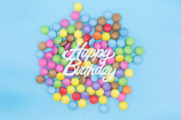 Invitation for birthday party with smarties and the words happy birthday in white on blue background