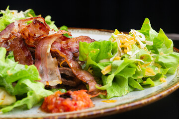 .salad with thin, crispy grilled bacon slices. salad of leaves, pork and cheese