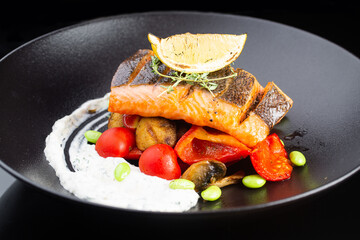 grilled salmon steak. grilled vegetables with fresh tomatoes. on black background