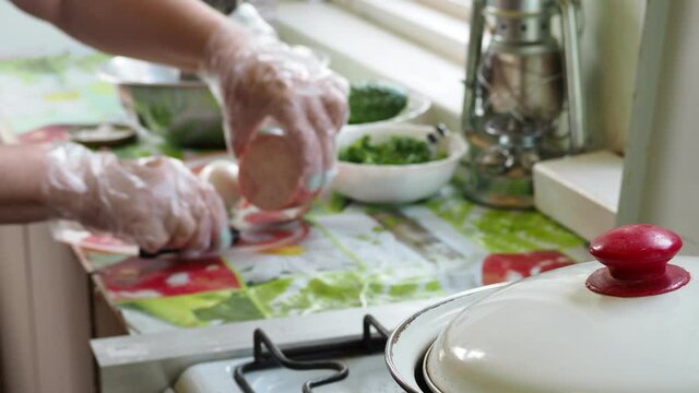 Cooking simple food. The cook puts boiled eggs and ham on the stor to prepare the dish against the background of a pan from under the lid of which steam is coming.. Out of focus.