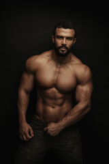 Obraz na płótnie Canvas Fitness handsome and shirtless man standing on black background