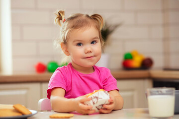 happy baby sitting at the table in the kitchen and eating with an appetite