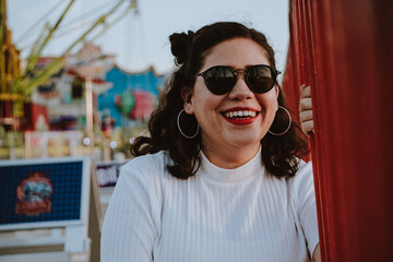 Mujer latina con gafas de sol en el atardecer de un parque de diversiones