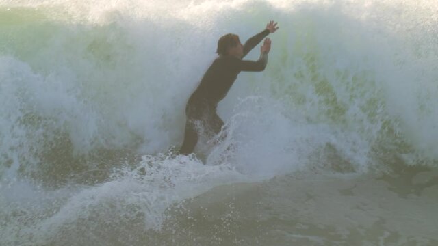 This slow motion video captures the moment a surfer jumps off his board and over a dangerous wave to avoid a huge ocean wipe out.