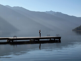 Woman in yoga pose by a lake