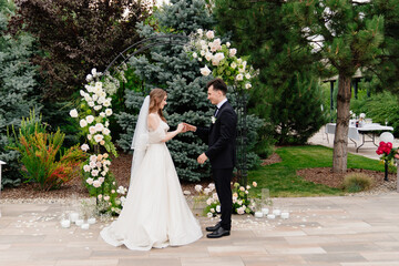 outdoor wedding ceremony in an arch of living flowers.newlyweds exchanged rings