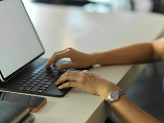 Female hands typing on tablet keyboard on the table in office room