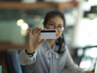 Businesswoman showing credit card in blurred background