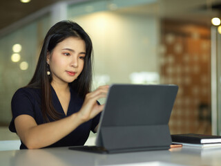 Female office worker working with digital tablet in office room