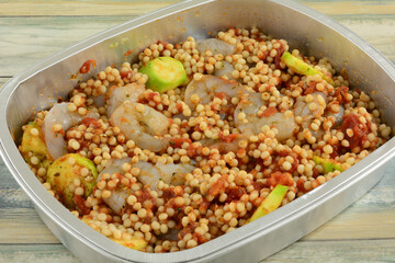 Raw shrimp, vegetable and pearl couscous pasta casserole in foil baking pan