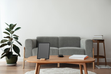 Digital tablet with blank black screen on a wooden table