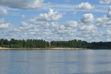 Summer landscape with a river and fluffy white clouds in the sky. Rybinsk, Russia, Volga river.
