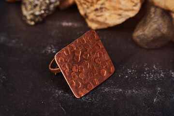 Copper ring in the shape of a square sheet handmade on a black textured background. Jewelry product. Special gifts   
