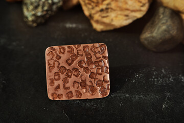 Copper ring in the shape of a square sheet handmade on a black textured background. Jewelry product. Special gifts       