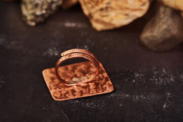 Copper ring in the shape of a square sheet handmade on a black textured background. Jewelry product. Special gifts          