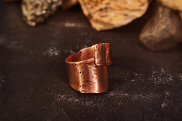 Copper ring with tubular shape handmade on a black textured background. Jewelry product. Special gifts           