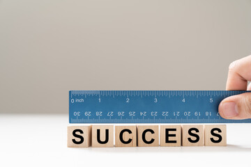 Measure success word using blue ruler, representing a review, evaluation or assessment of an...