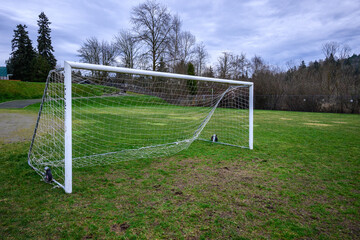 Soccer goal on a wet and worn grass field, stormy sky in the background
