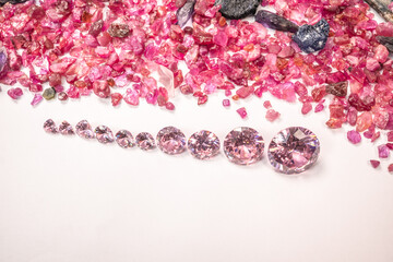 pink sapphires diamonds in different size in one row on white background .place in front natural red garnet tumbled stones