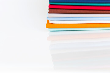 Colorful cotton fabric stack on white background, laundry or textile industry concept