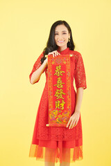 Portrait of pretty young Asian woman showing wall decoration for Chinese New Year celebration with best wishes inscription