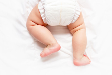 Cute caucasian infant baby in white nappy on light grey blanket. Top view. Banner format. Copy space. Diaper change and care of baby's skin. 