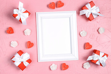 Empty white frame with gifts, candles hearts and roses on pink background. Valentine's day concept.