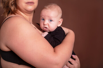 Overweight mother , with fat body after childbirth, holding newborn baby on the studio