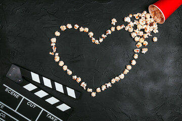 Movie clapper board and popcorn heart on black background with copy space. Love story movies.