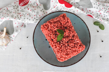 Minced Meat, Fresh raw beef whit black pepper, mint, basil and garlic served on plate on white wooden background/ Fresh raw minced meat ready for cooking/ Food preparation
