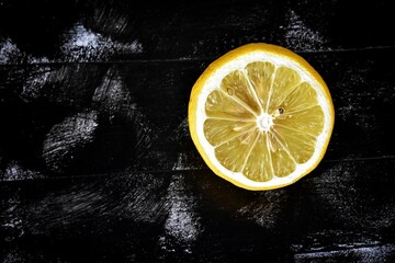 Fresh ripe lemons on dark stone background/ Half ripe lemon on a black background. Lemon cutaway....