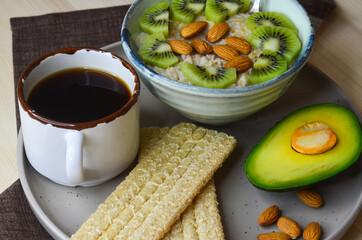 Healthy, natural and hearty breakfast, milk oatmeal with kiwi and almonds