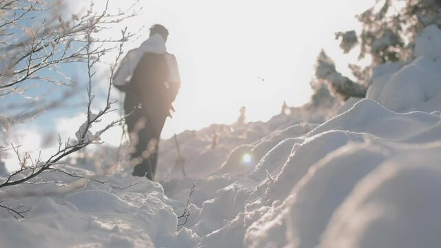 A young woman is climbing a snow-covered road up a mountain. The snow is glistening in the sun. Mount Pikui.