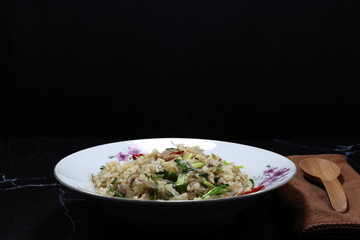 Fried and stirred jasmine rice with onion, chilly and fish meat serving on the plate. Traditional spicy street food menu in Asia restaurant. 