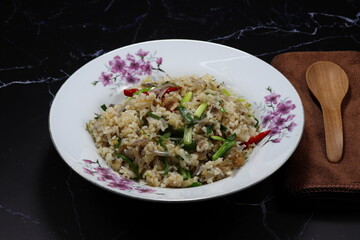 Fried and stirred jasmine rice with onion, chilly and fish meat serving on the plate. Traditional spicy street food menu in Asia restaurant. 