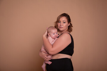 Overweight mother , with fat body after childbirth, holding newborn baby on the studio