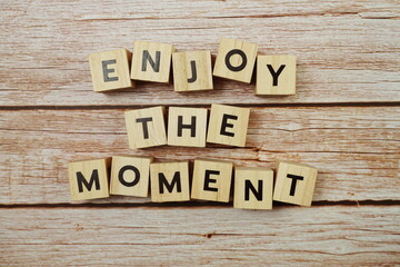 Enjoy The Moment alphabet letter on wooden background