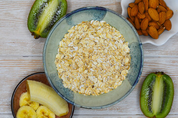 Ingredients for making porridge, oatmeal, nuts almond, banana, kiwi top view, healthy food and hearty breakfast with fruits