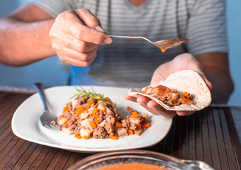 MAN EATING MEAT WITH VEGETABLES AND TORTILLA