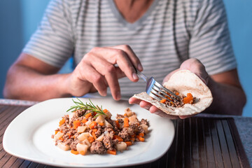 MAN EATING MEAT WITH VEGETABLES AND TORTILLA