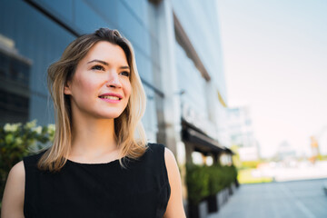 Business woman standing outside office buildings.