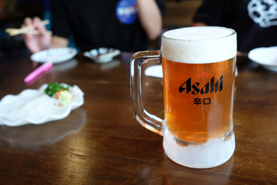 BANGKOK, THAILAND - NOVEMBER 20, 2020: Asahi Beer on Wood Table in japanese restaurant, It's a famous Japanese super dry beer and distributed by Asahi Breweries, Ltd.