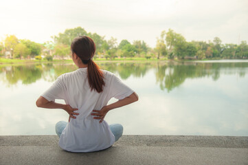 An Asian woman relaxing by the water in a park