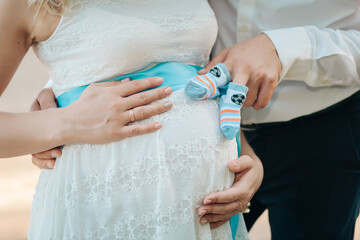 Loving hands hug the belly of a pregnant girl