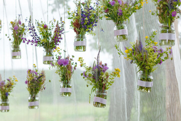 Original wedding floral decoration in the form of mini-vases and bouquets of flowers hanging from the ceiling