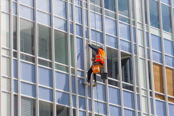 Outside of the building washing the glazing of the facade of a multi-storey building climbers clean windows.