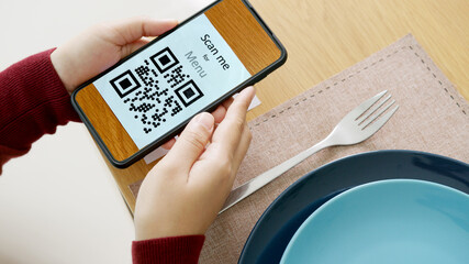 Hand's customer scan QR code for online menu service at table in restaurant during pandemic...