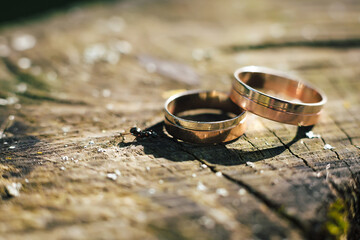 Beautiful wedding rings lie on wooden surface against background of bouquet of flowers. Declaration of love, spring. Wedding card, Valentine's Day greeting. Wedding rings. Wedding day details